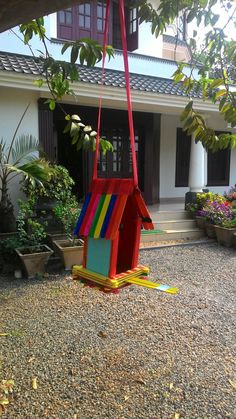 a colorful birdhouse hanging from a tree in front of a house