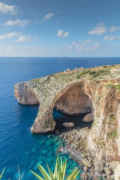 the ocean is blue with clear water and an arch shaped rock formation in the middle