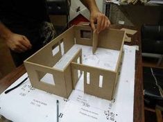 a man is making a model house out of cardboard