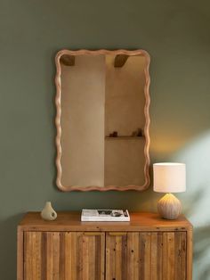 a wooden cabinet with a mirror above it and a lamp next to it on the side