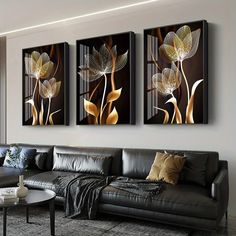 three paintings on the wall above a couch in a living room with black leather furniture