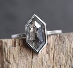 a close up of a ring on top of a piece of wood with a black diamond in the center