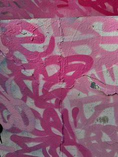 pink and white graffiti on the side of a building with black birds flying around it