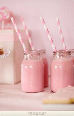 two pink milkshakes are sitting next to each other with straws in them