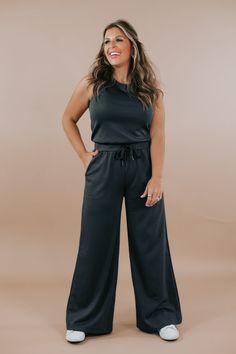 Introducing the Wide Leg Drawstring Jumpsuit in dark Charcoal, a sleek and versatile piece that effortlessly combines style and comfort. Crafted with soft and flowy fabric, this jumpsuit offers both elegance and ease of movement. Pair with a denim jacket for a laid-back look. Wide leg jumpsuit Drawstring jumpsuit Athleisure material Comfy Functional pockets Elastic waist band Adjustable tie Button closure in the back 49%polyester, 45% rayon, 6% spandex Imported MEASUREMENTS:S: INSEAM: 28”M: INSEAM: 28”L: INSEAM: 28 1/2” Model Specs: Karli is wearing a size small in the photo. How will this item fit you? Check out our MODEL SPECS (Typical Sizing - Karli: S-Size 5/26 - 5ft 2in, Emily: S-Size 3/25 - 5ft 5in, Syd: L/XL- Size 15/ - 5ft 8in)Need help with sizing? No problem! Join our VIP group o Drawstring Jumpsuit, Look Wide Leg, Flowy Fabric, Vip Group, Everyday Chic, Chic Boutique, Wide Leg Jumpsuit, Waist Band, Athleisure