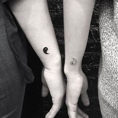 two people holding hands with tattoos on their arms and one has a crescent tattoo on the wrist