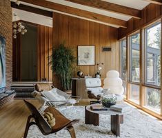 a living room filled with furniture and lots of wood paneling on the walls next to windows