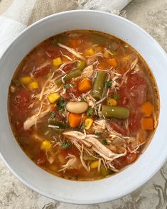 a white bowl filled with soup and veggies on top of a marble table