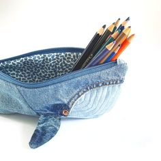 a pencil holder with several pencils in it and a pair of scissors sticking out of the pocket