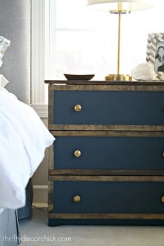 a blue dresser sitting next to a bed in a room with a lamp on top of it