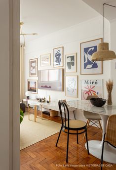 a dining room table with chairs and pictures on the wall