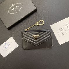 a black purse with a gold keychain and some cards