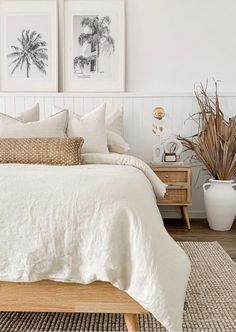 a bed with white linens and pillows in a bedroom next to two pictures on the wall