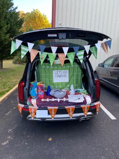 the back end of a car with its trunk open and decorations hanging from it's roof