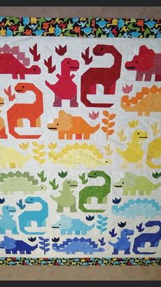 a quilted wall hanging with numbers and dinosaurs on it's sides, in the shape of animals