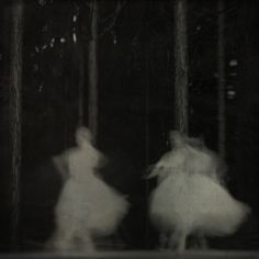 two women in white dresses are walking through the woods