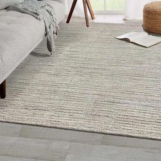 a living room with a gray couch and white rugs on the floor in front of a window