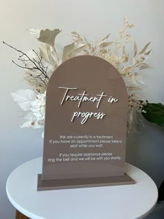 a sign that says treatment in progress on top of a table with flowers and leaves