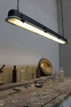 an industrial style light hanging over a wooden counter with bottles and other items on it