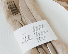 a table setting with silverware and place cards on the napkins, along with a knife and fork