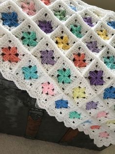 a crocheted blanket is sitting on top of a suitcase