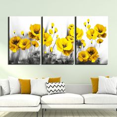 three yellow flowers on a white wall in a living room with couches and pillows