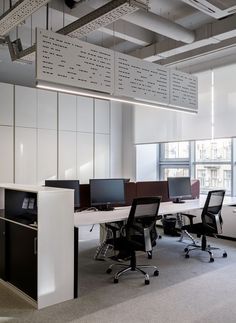 an office cubicle with multiple computer screens and desks, along with other office furniture