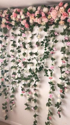 an arrangement of pink and white flowers hanging on a wall