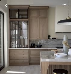 a kitchen with marble counter tops and wooden cabinets, along with an island in the middle