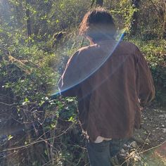 a man standing in the woods with his back to the camera and looking at something behind him