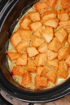 a crock pot filled with tater tots on top of a wooden table