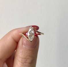 a woman's hand holding an engagement ring with a diamond in the middle and a red band around it