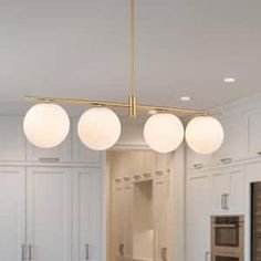 a kitchen with white cabinets and three lights hanging from the ceiling over the stove top