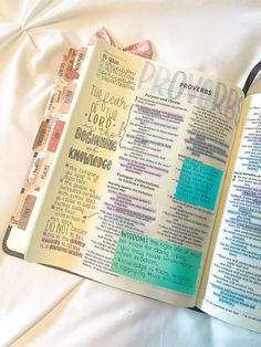 an open bible laying on top of a white sheet with words written in different languages