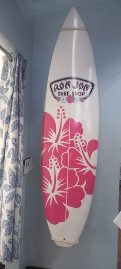 a surfboard is hanging on the wall next to a window in a room with blue walls