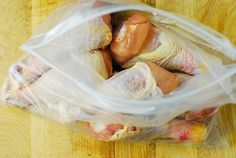 a plastic bag filled with meat on top of a wooden table