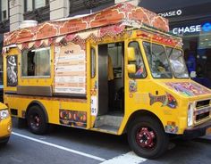 a yellow food truck is parked on the side of the street