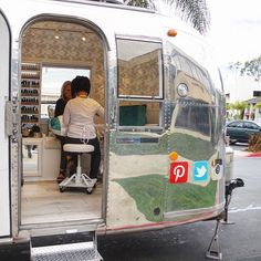 two people are sitting in the back of an airstream that is parked on the side of the road