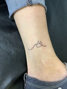 a woman's foot with a small wave tattoo on it