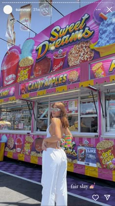 a woman standing in front of a pink food truck with lots of candy on it