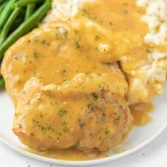 meatloaf with gravy and mashed potatoes on a plate next to green beans