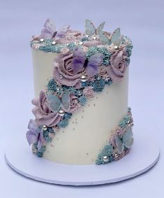 a white cake with purple flowers and butterflies on it