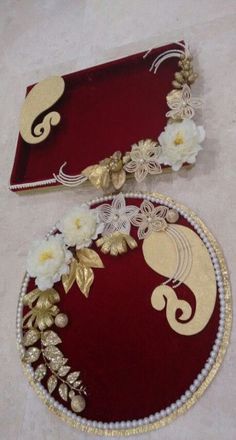 two red trays with gold and white flowers on them sitting on a floor next to each other