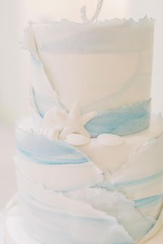 a white and blue wedding cake with starfish on top