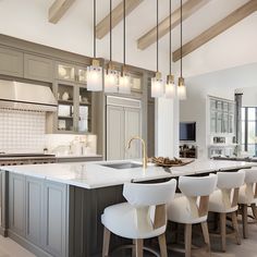 a large kitchen with an island and bar stools in the center, surrounded by gray cabinets