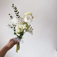 a hand holding a bouquet of white flowers