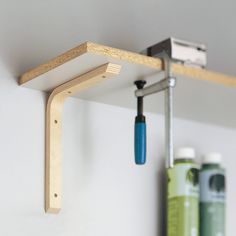 a wooden shelf with some tools hanging from it's side and another item on the wall behind it