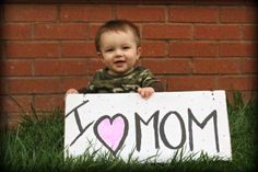 a little boy holding a sign that says mom