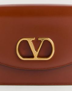 Valentino Garavani Vain shoulder bag in shiny calfskin with metallic VLogo Signature detail. The bag can be carried on the shoulder/cross body thanks to the sliding chain. - Antique gold-finish hardware - Magnetic closure with antique brass-finish VLogo - Nappa lining. Interior: two compartments, zip pocket and slip pocket Shoulder strap drop length: min. 27 cm - 52 cm max. / min. 10.6 cm to max. 20.4 in. - Dimensions: W24xH16xD8 cm / W9.4xH6.2xD0.7 in. - Made in Italy Luxury Shoulder Bag With Metal Logo, Elegant Brown Bags With Gold-tone Logo Plaque, Elegant Brown Bag With Gold-tone Logo Plaque, Designer Formal Shoulder Bag With Logo, Luxury Brown Bag With Gold-tone Logo Plaque, Luxury Shoulder Bag With Logo, Gold Leather Bag With Logo, Designer Formal Shoulder Bag With Metal Logo, Designer Calf Leather Bags With Logo