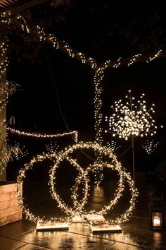 some lights that are on the ground in front of a tree with two rings attached to it